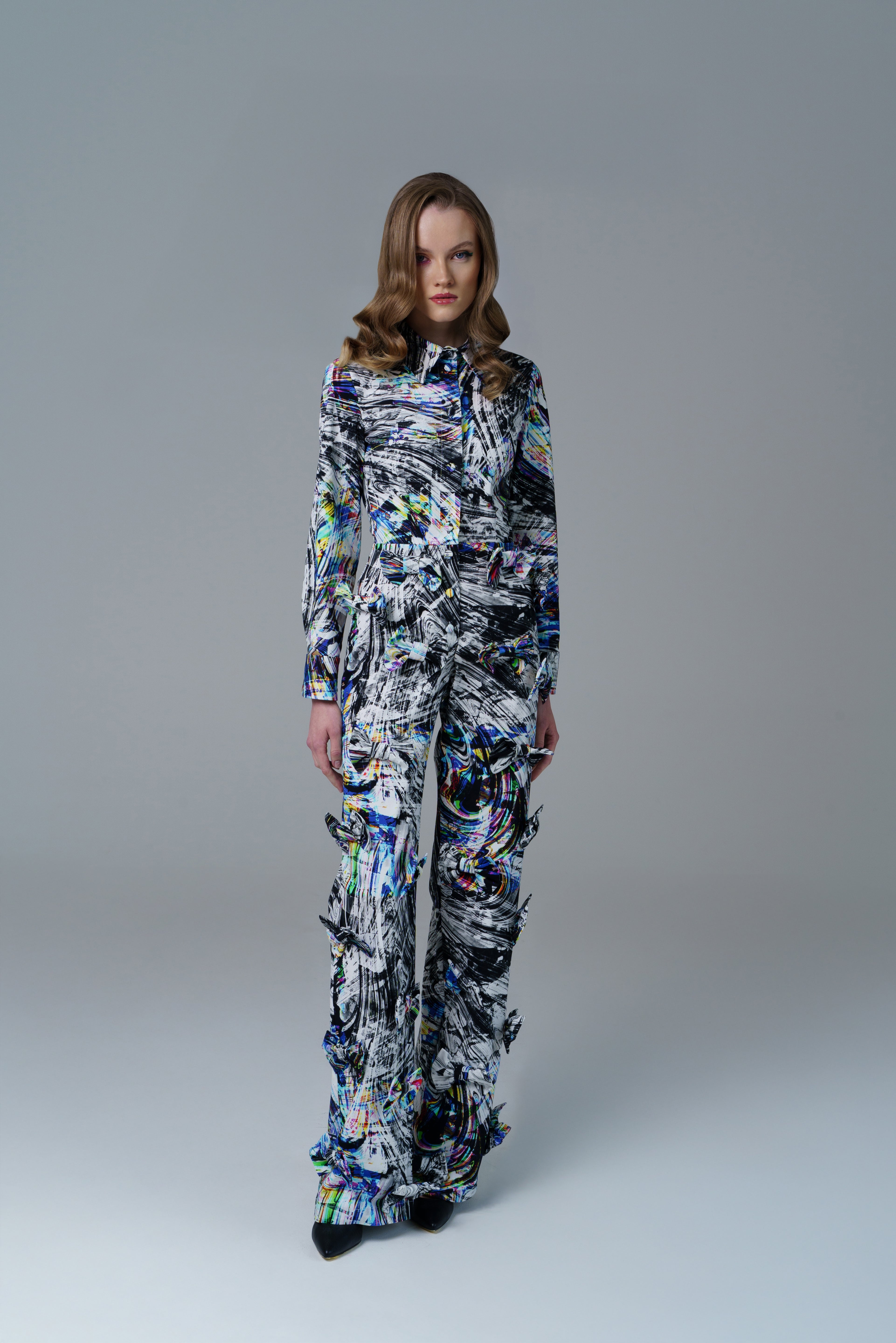 Bold abstract print top with front bow detail and structured fit. A modern, artistic statement piece.